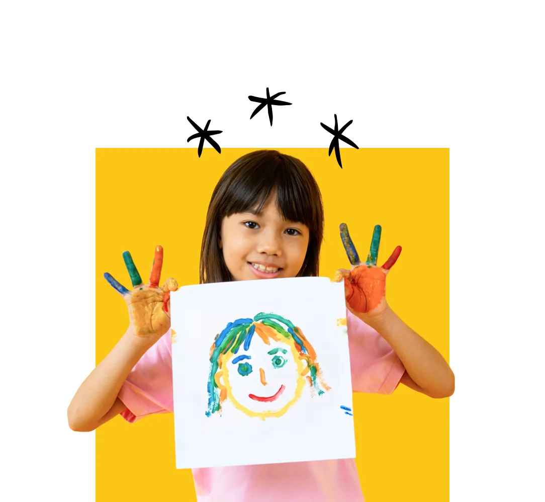 A young girl smiling and holding up a finger painting, with her hands covered in paint.